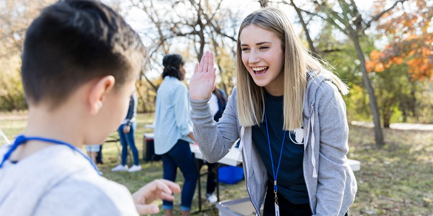 A young community worker at a group activity for children at a park.