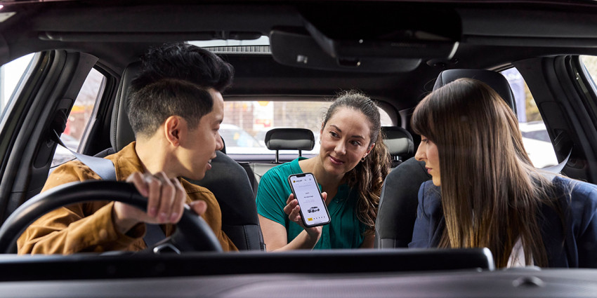 Three people in a car looking at ANCAP Safety ratings on a mobile phone